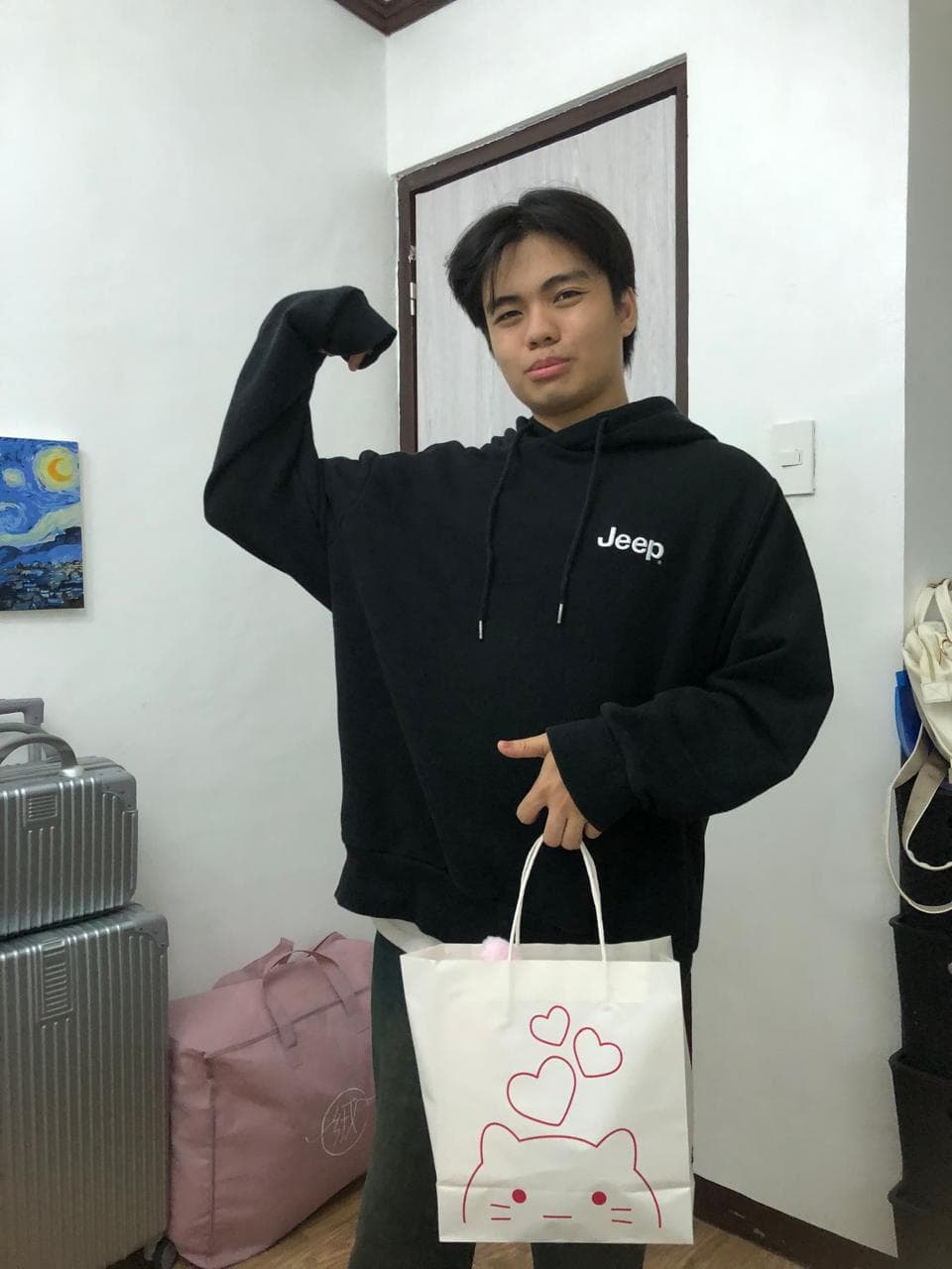 Mark Milca in a black hoodie, smiling and flexing one arm